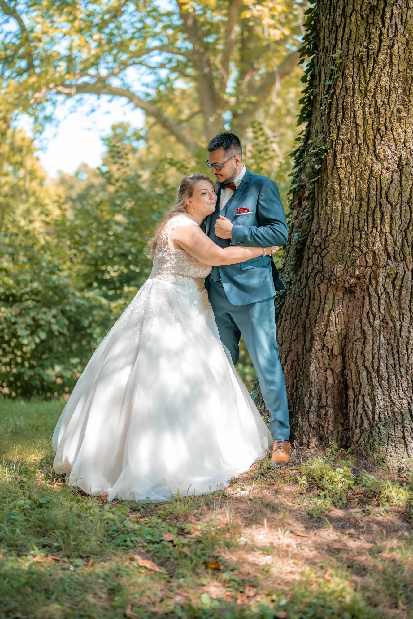 Couple enlacé contre un grand arbre en forêt