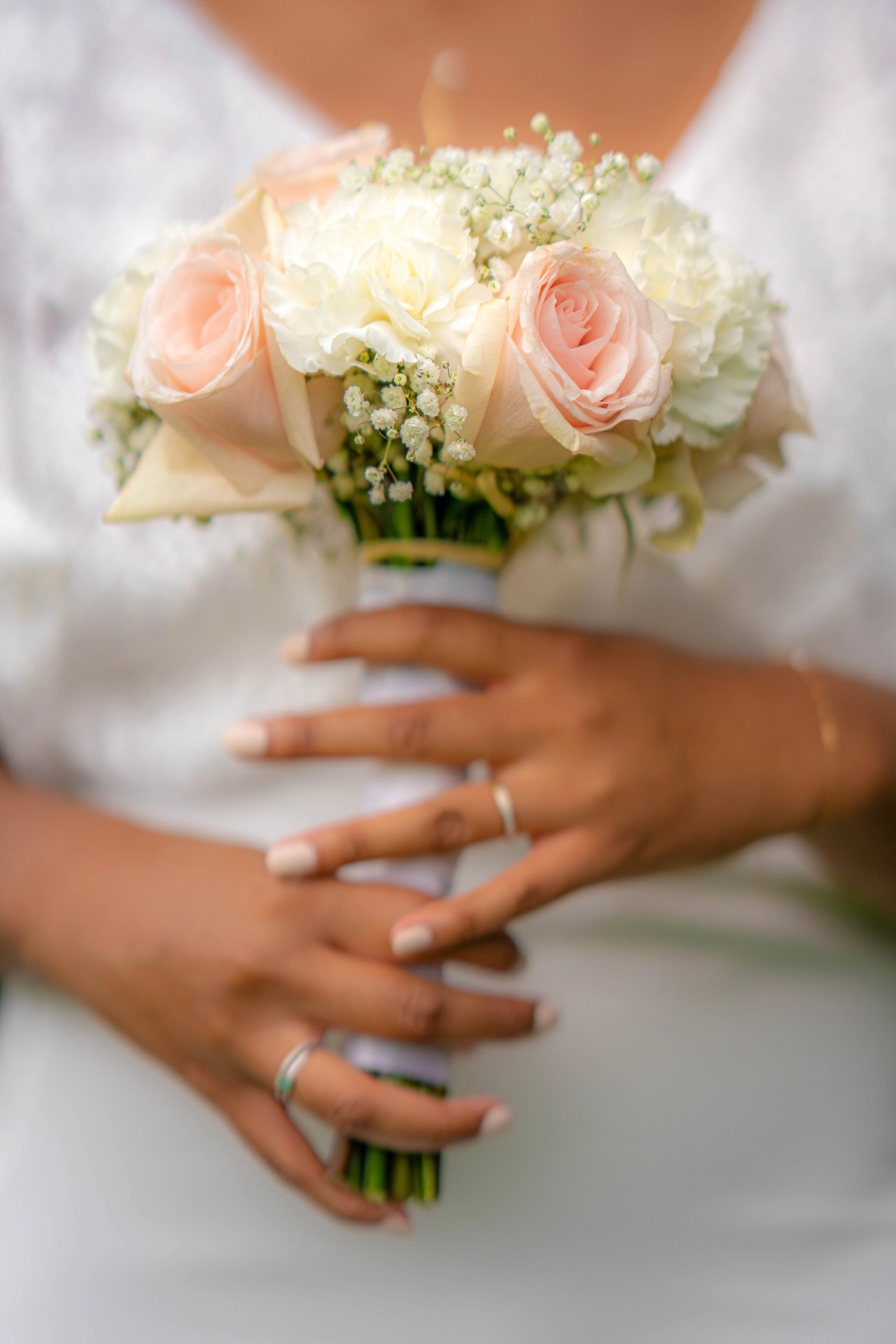 Mains de la mariée tenant un bouquet de roses